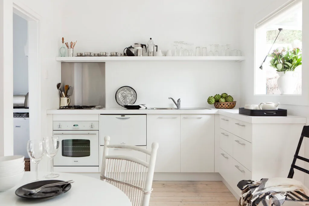 White l-shaped kitchen in a coastal weekender.