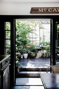 French doors leading from a kitchen into a courtyard decorated with ecclectic vintage plant pots.