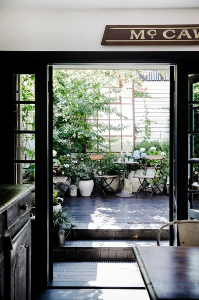 French doors leading from a kitchen into a courtyard decorated with ecclectic vintage plant pots.