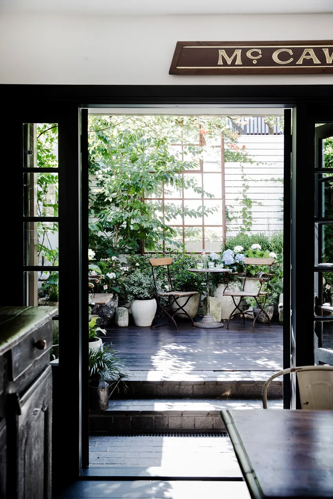 French doors leading from a kitchen into a courtyard decorated with ecclectic vintage plant pots.