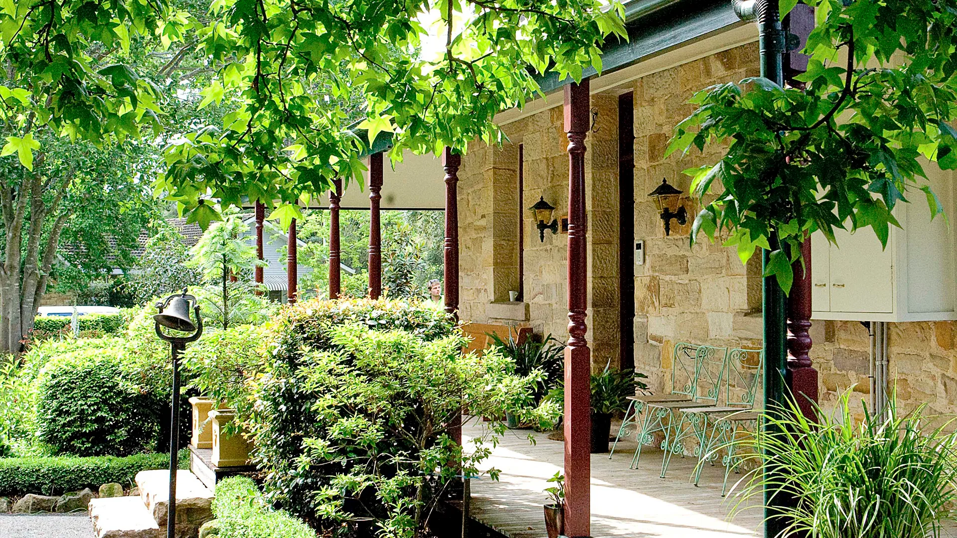 Sanstone homestead surrounded by lush greenery.