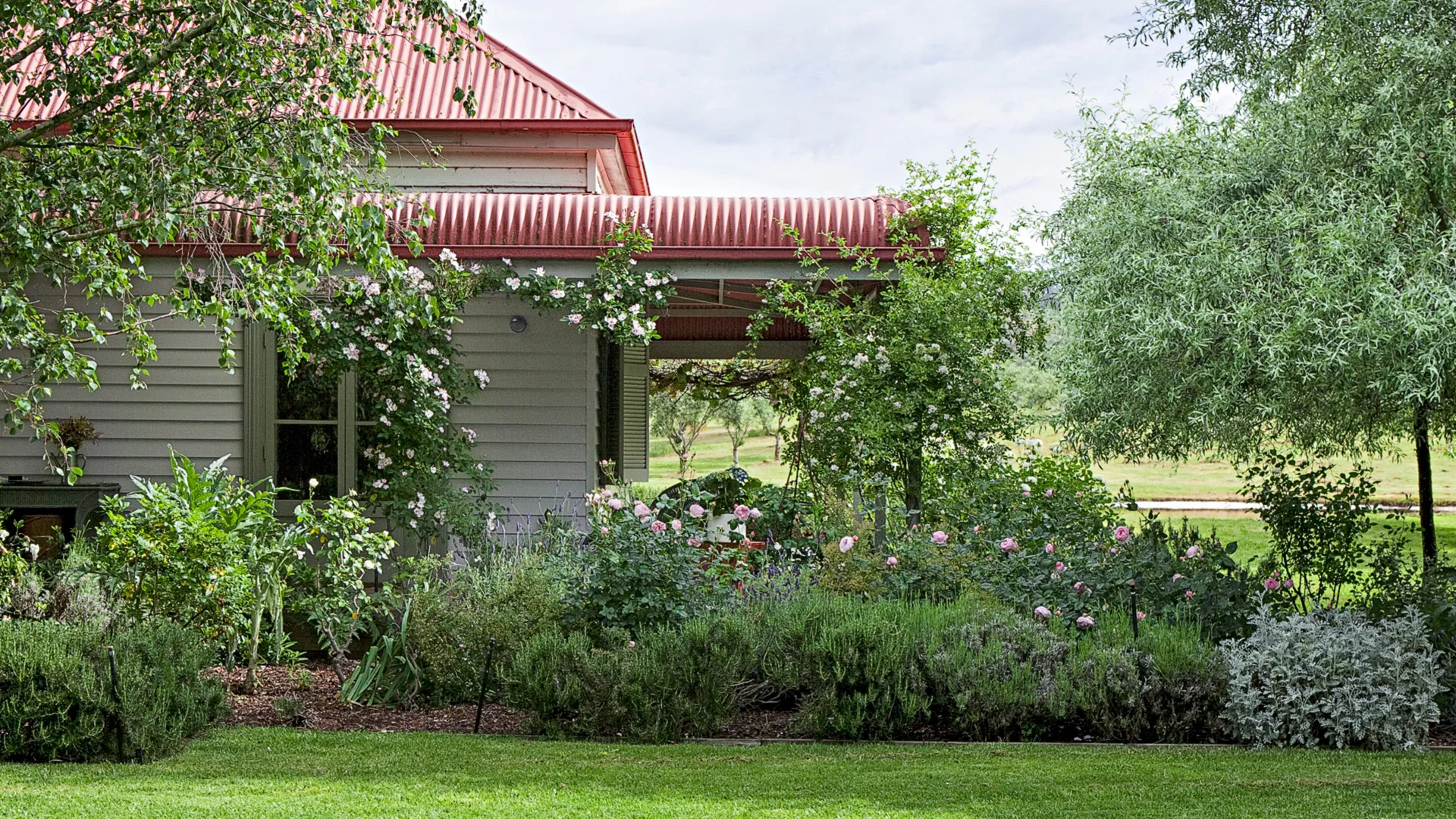 Cottage farmhouse surrounded by lush green cottage garden designed by Paul Bangay.