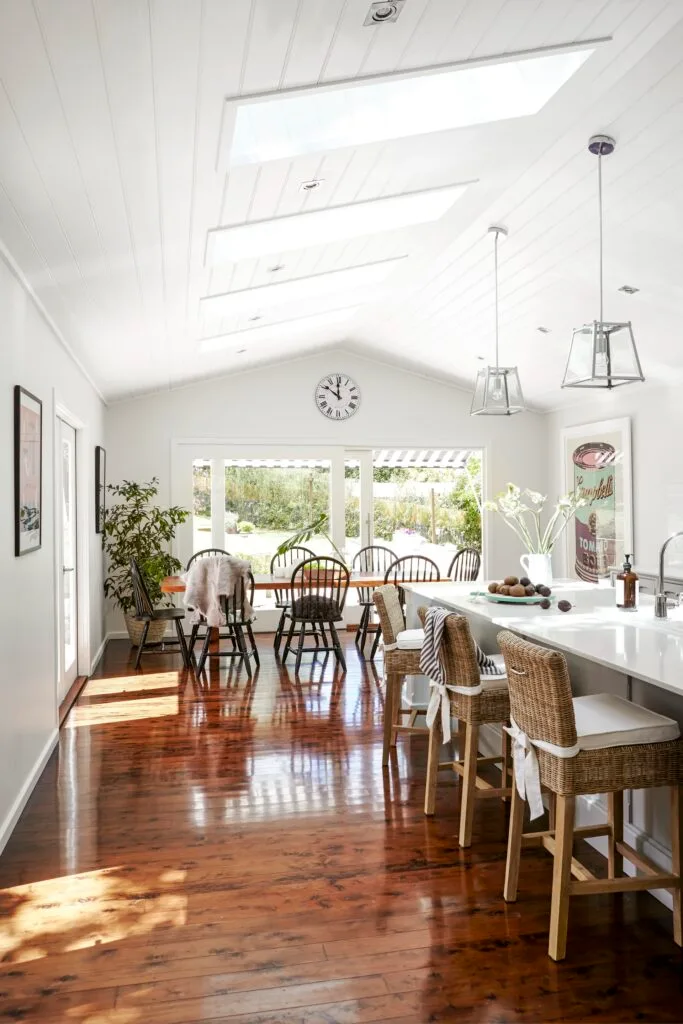 Open plan kitchen and dining room with skylights and timber flooring.