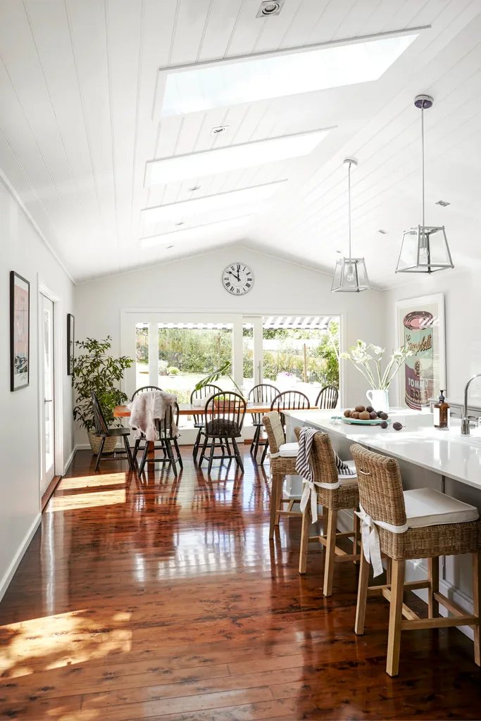 Open plan kitchen and dining room with skylights and timber flooring.