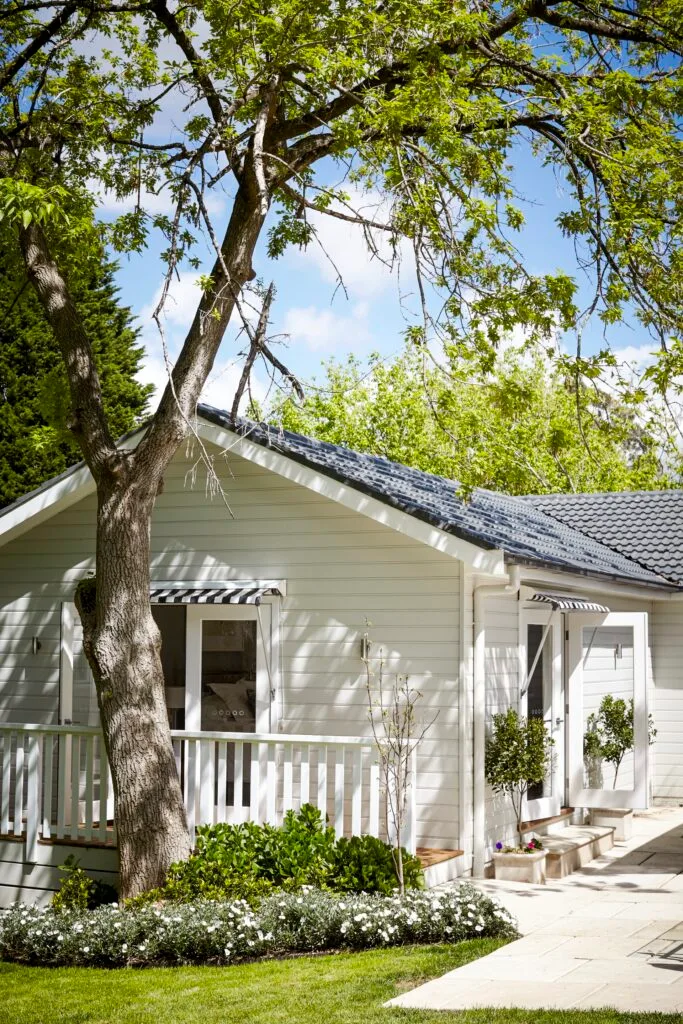 Exterior of a renovated cottage in Bowral with black and white awnings.