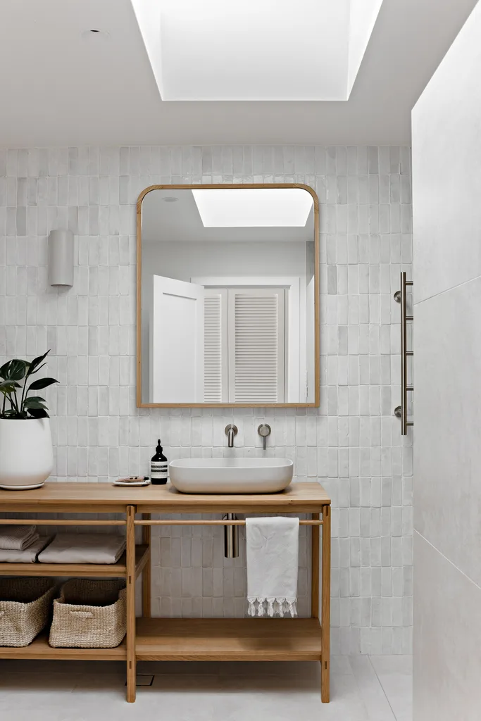 Modern bathroom with feature wall tiles, timber vanity, bowl sink and indoor plant.