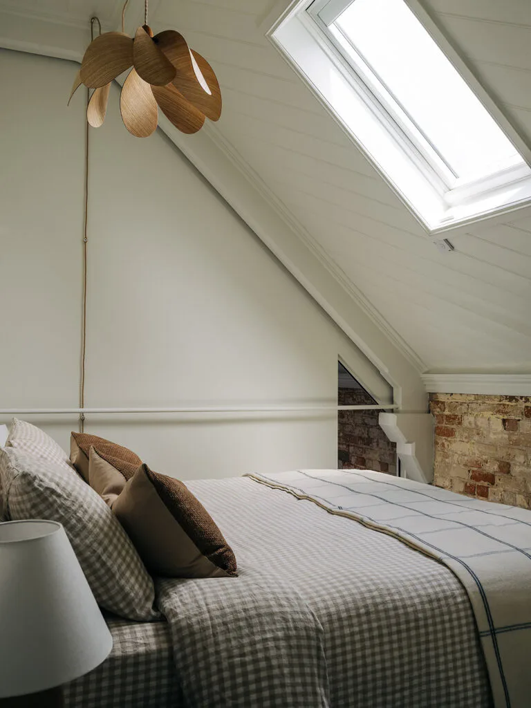 Bed in a boutique hotel apartment with a Duncan Meerding pendant light overhead.