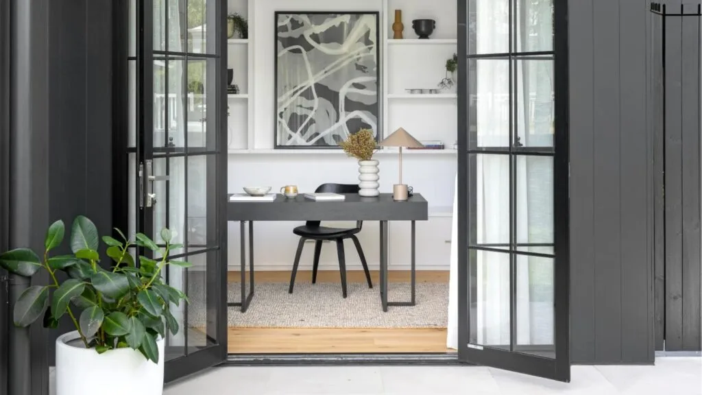 Modern home office viewed throw open steel framed black doors.