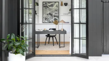 Modern home office viewed throw open steel framed black doors.