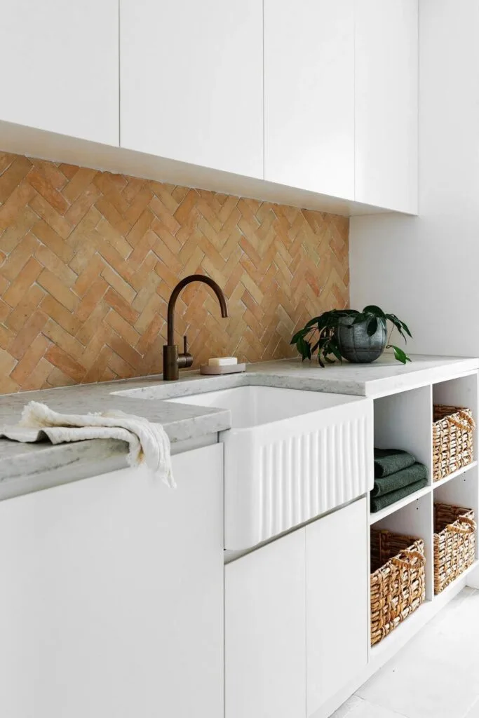 Terracotta, white and marble laundry with a mix of open and closed shelving.