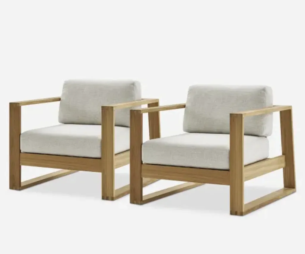 Two outdoor furniture armchairs with wooden frames and cream cushions