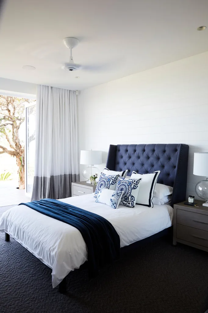 Deborah Hutton's bedroom at her bronte home, complete with blue upholstered bed head and white sheets with blue toned cushions.