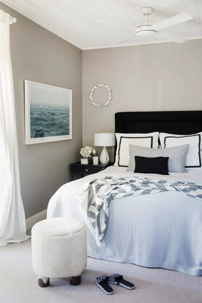 Black and white Hamptons style bedroom with coastal print on the wall.