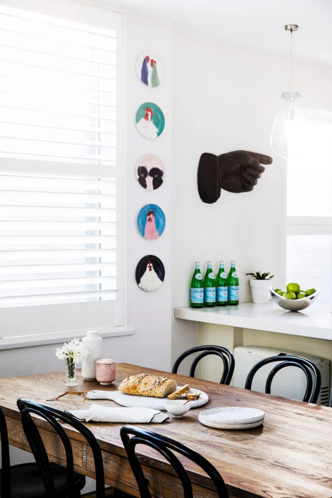 Dining room with a timber table and decorative plates on the wall.