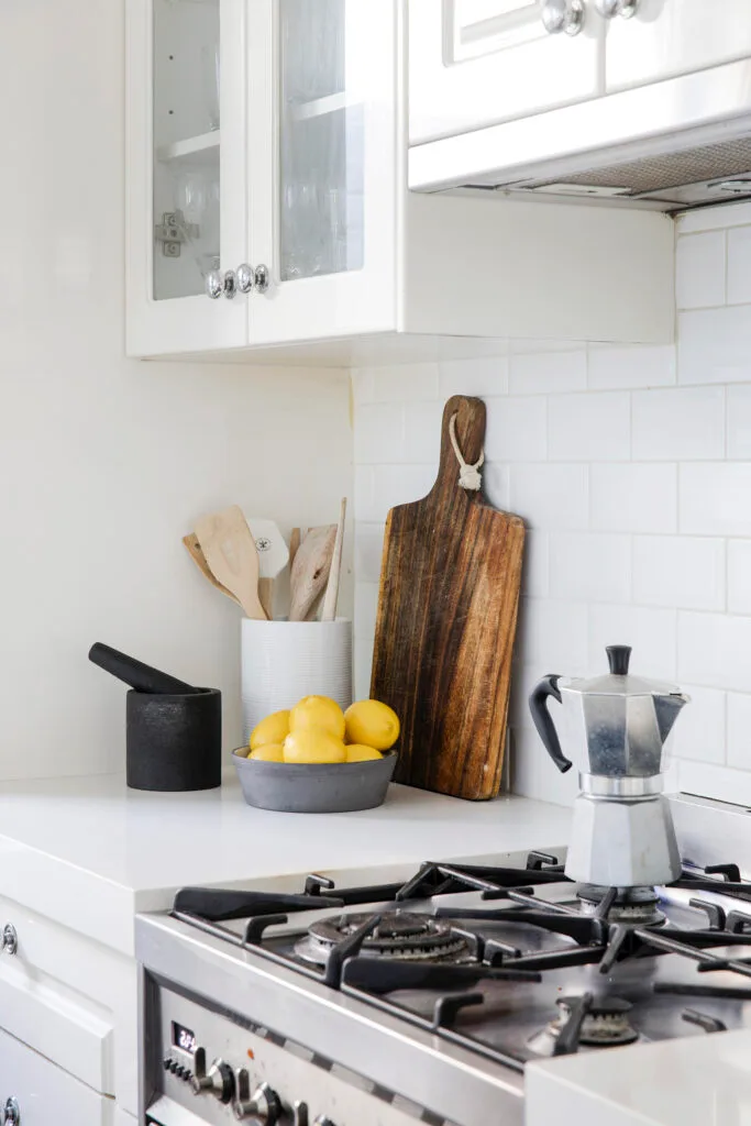 Coffee pot on the stove of a white shaker kitchen with white subway tile splashback.