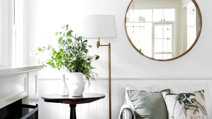 Hamptons style living room with vase of fresh flowers and round mirror