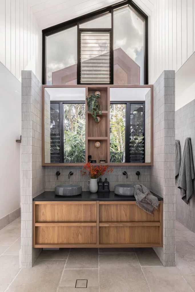 Contemporary Australian bathroom in Shelley Craft's former Belongil Beach home featuring timber banity, dual sinks and tapware in brushed gunmetal.