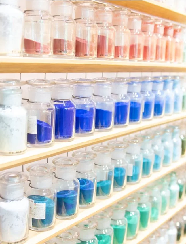 Bottles of pigment on wooden shelves from an art lab in Tokyo