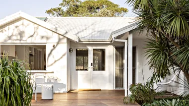 Landscape image of a white beach house exterior with large back deck.