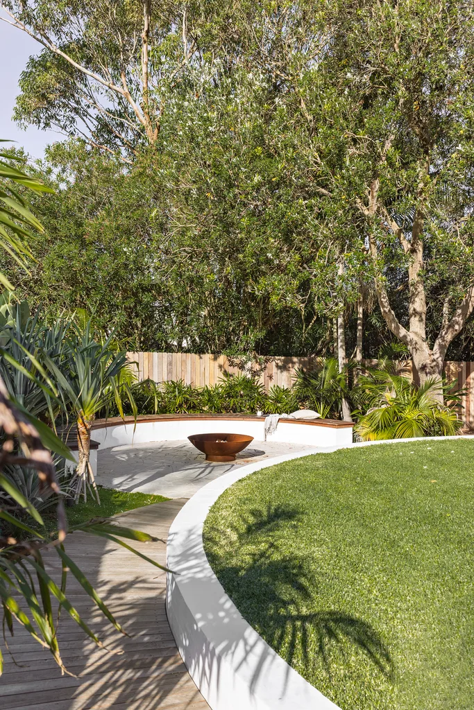 Coastal, tropical garden with curved wall, fence and lawn.