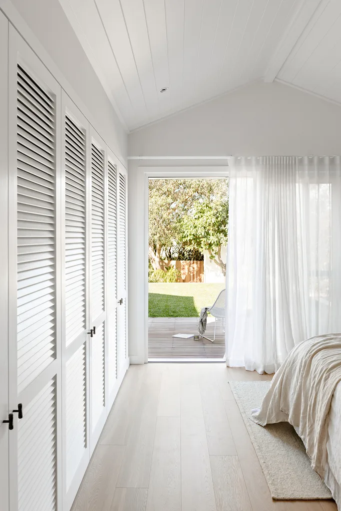 Coastal style bedroom with exterior door, and wardrobe doors with louvred fronts.