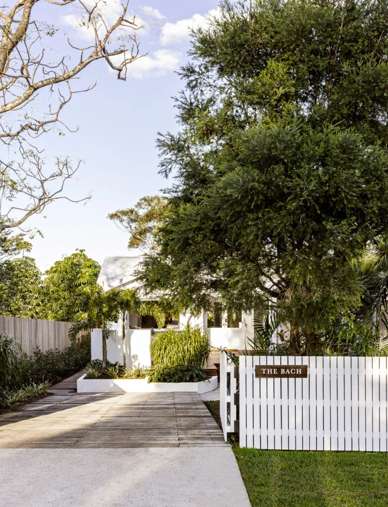 Exterior of The Bach, a renovated beach house on the NSW South Coast featuring a white picked fence and long driveway.