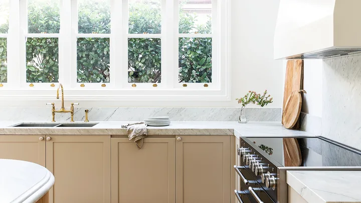 Marble and neutral kitchen with oven, rangehoood and integrated dishwasher.