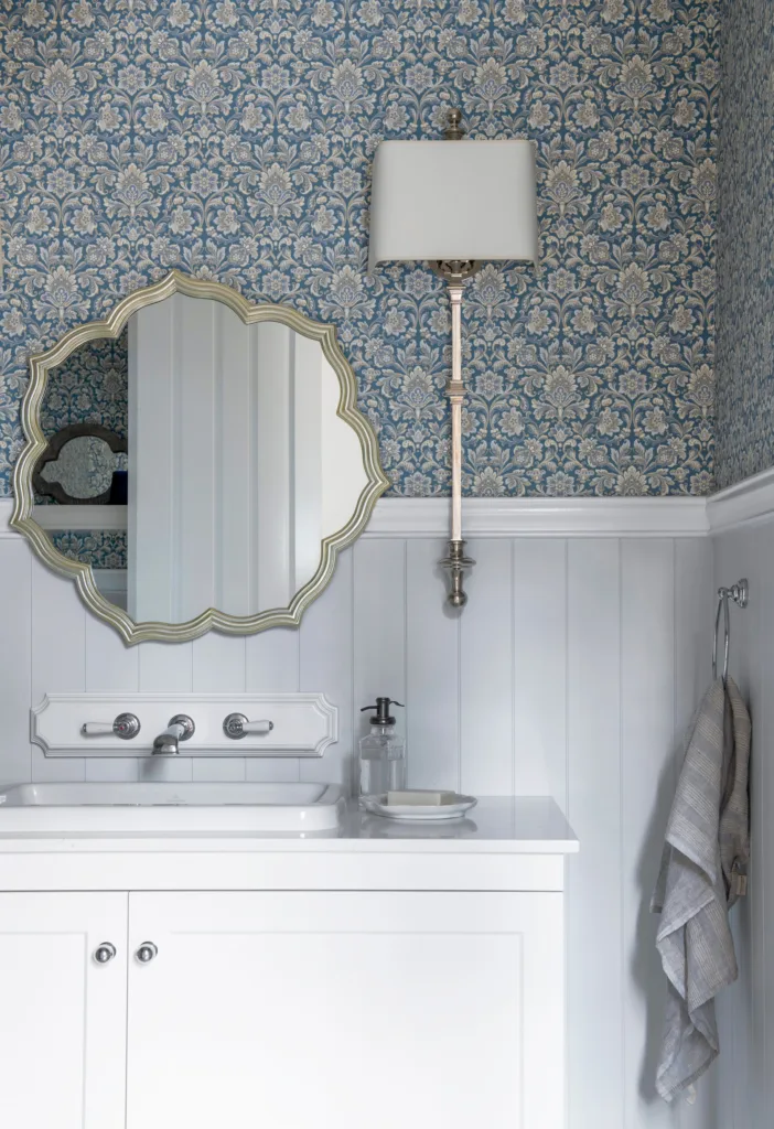 Wallpapered Hamptons style powder room with petal shaped mirror