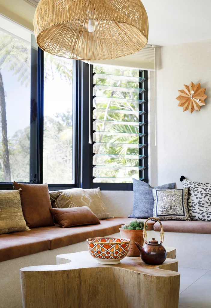 Contemporary home with window seat beneath louvred windows and an organically shaped solid timber block coffee table