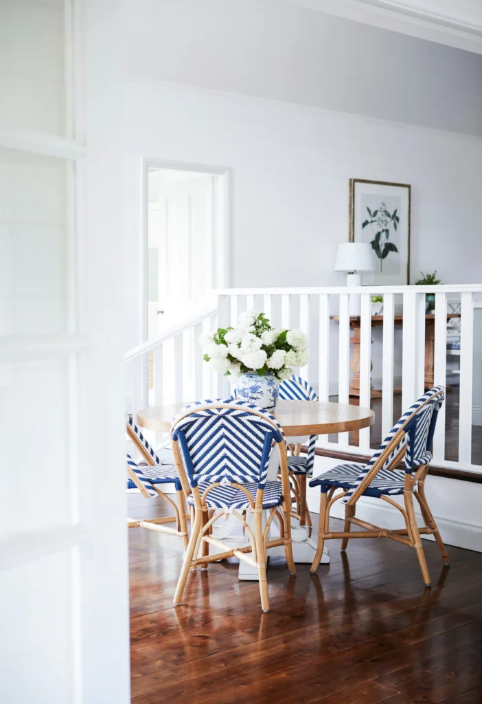 A round timber dining table set with four blue Parisian style chairs.