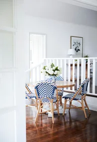 A round timber dining table set with four blue Parisian style chairs.