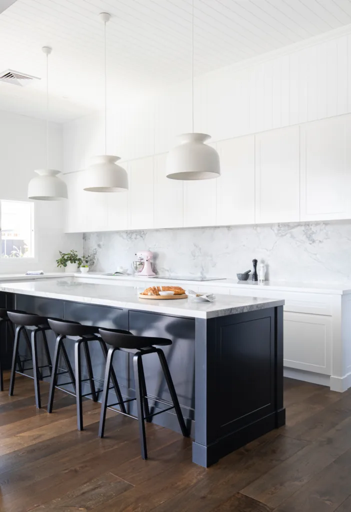 modern white kitchen with navy blue kitchen island cabinetry and marble benchtop and marble splashback