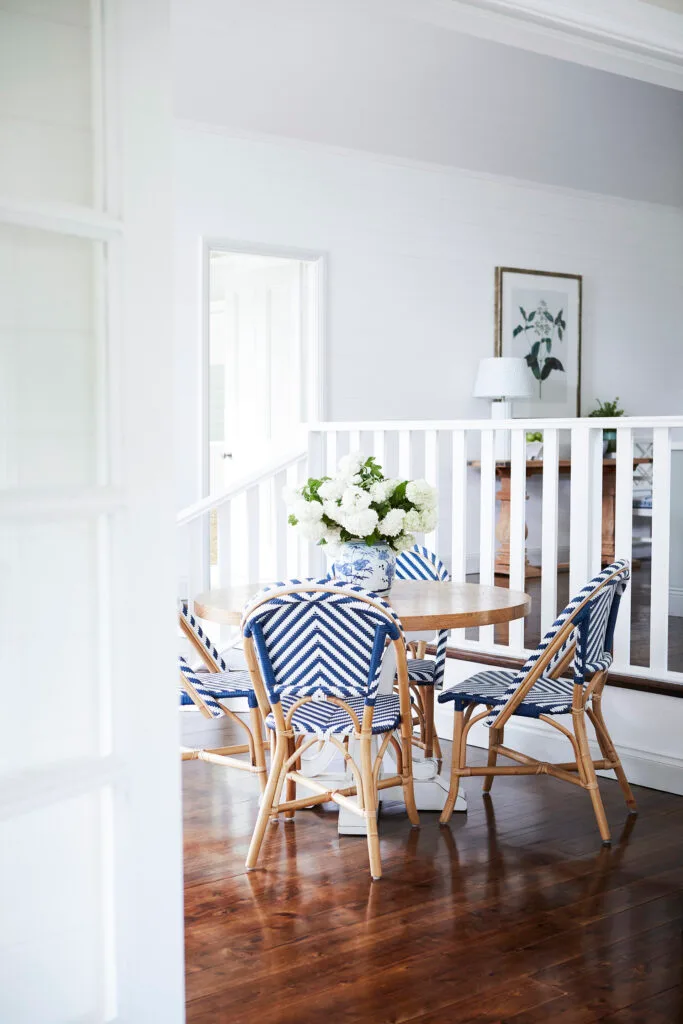 Timber breakfast table surrounded by blue bistro chairs in a country-meets-Hamptons style home in Bowral.