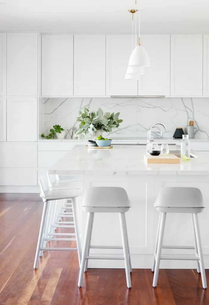 Modern white kitchen with marble-look splashback and white bar stools