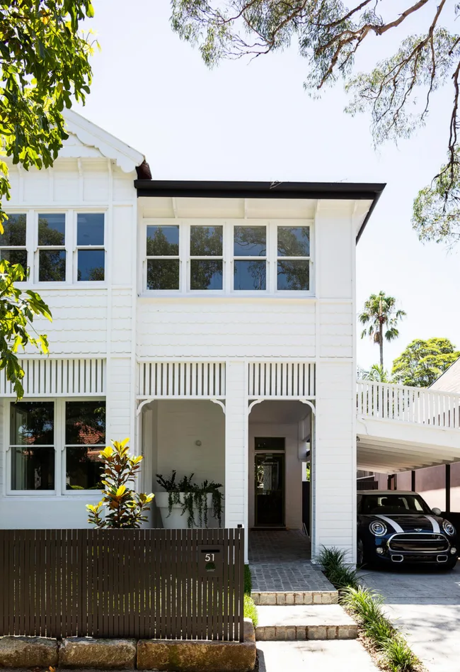 a white Victorian home with sash windows and contemporary landscaping