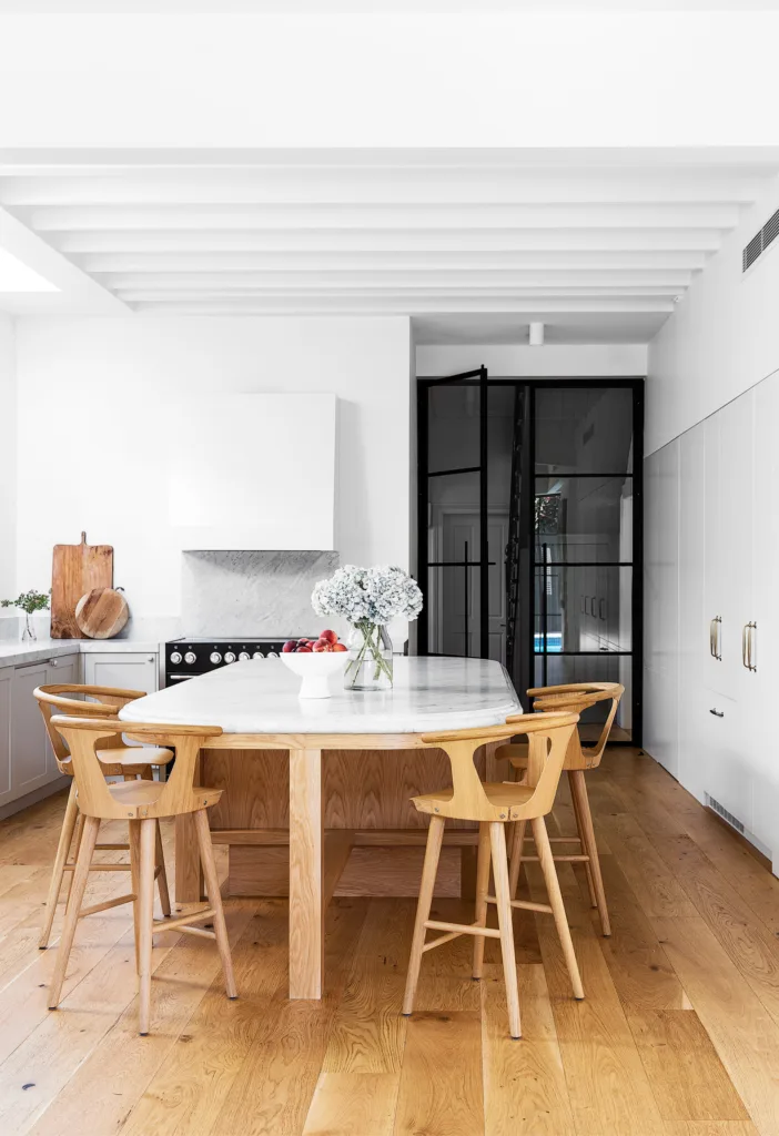 Modern kitchen design with large central kitchen island with marble benchtop and timber barstools