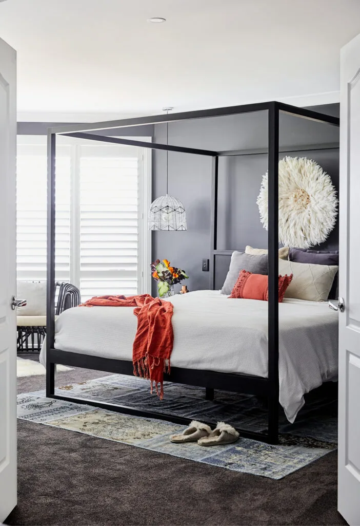 Dark grey painted bedroom with black four poster bed