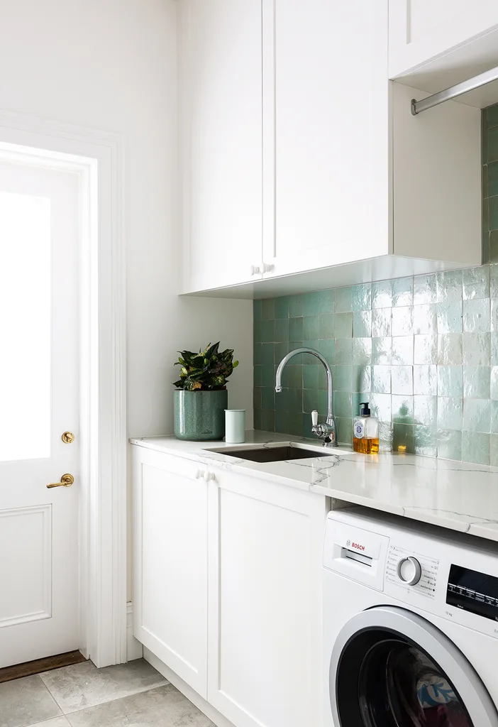 White laundry with green tiled splashback and external door.