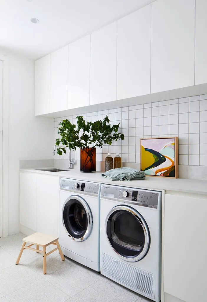 White laundry with vase of flowers and colourful artwork.