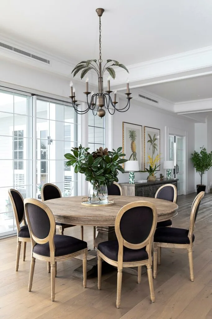 Modern Hamptons dining room with circular timber table and black dining chairs.