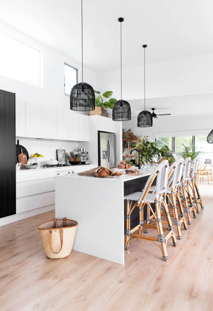 Modern coastal kitchen design with black rattan pendant lights and woven bar stools