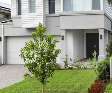 Grey home with white garage door and tidy front lawn