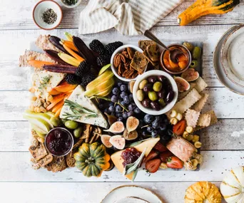 Assorted cheese, crackers, fruits and dips arranged on a cheeseboard