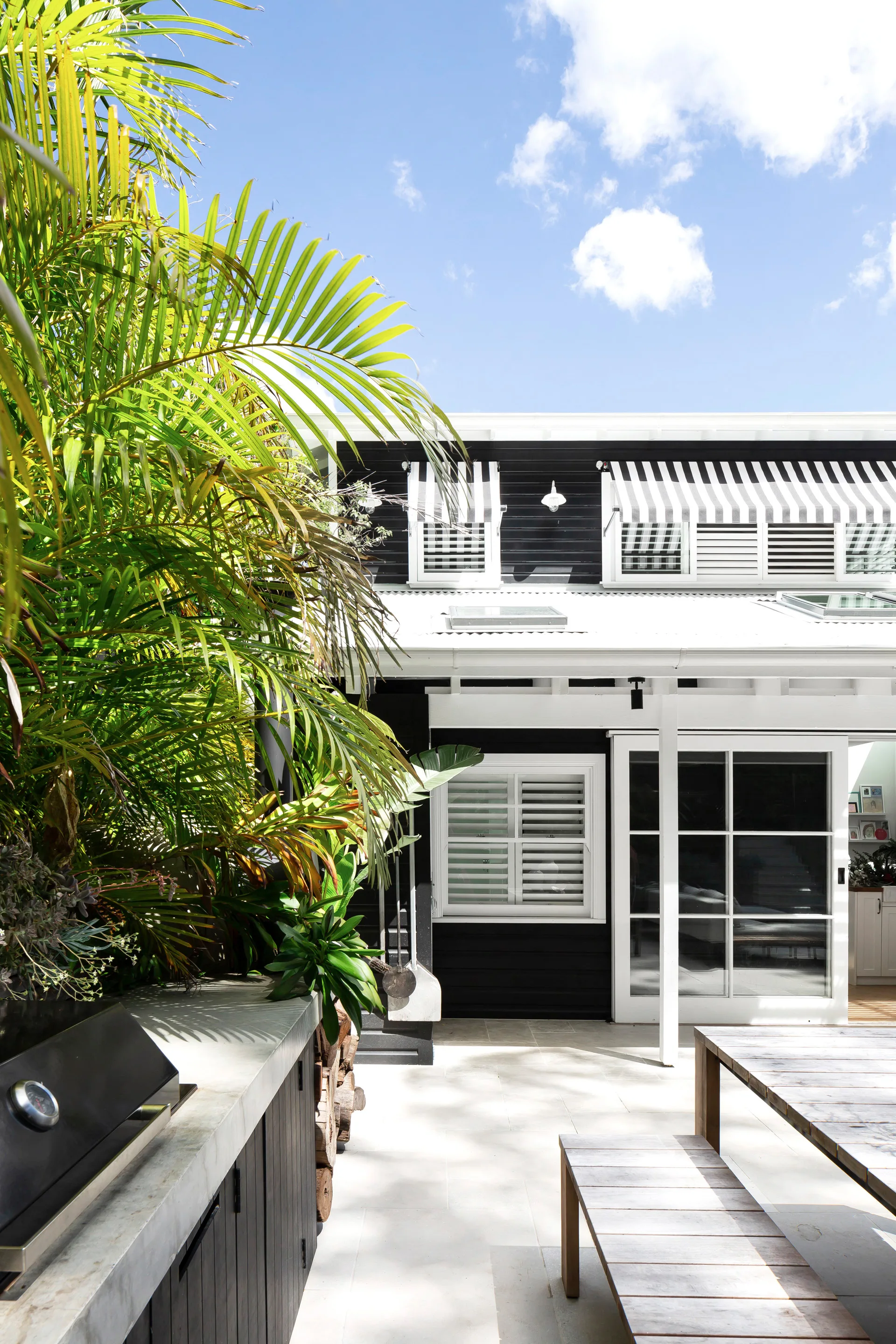 Coastal home rear exterior painted in Dulux Black and Lexicon Quarter with black and white awnings.