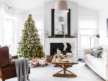 Christmas tree and decorations in a cozy living room with a fireplace, stockings, and a coffee table with gifts.