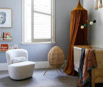 Blue baby nursery with wooden furniture and rust-coloured ceiling canopy