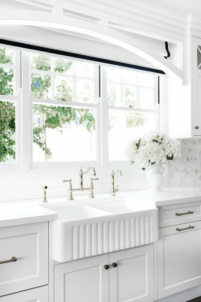 White marble kitchen with ceramic farmhouse sink.