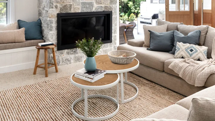 A modern farmhouse living room with a stone fireplace and chunky knitted throw on a lounge.