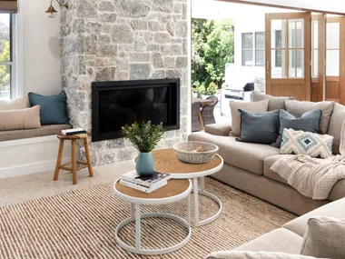 A modern farmhouse living room with a stone fireplace and chunky knitted throw on a lounge.