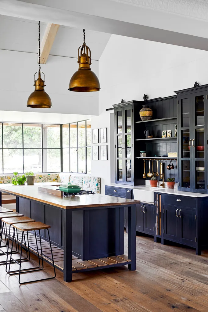 modern farmhouse style kitchen with navy blue cabinetry copper light fittings, timber benchtops and hardwood floors.